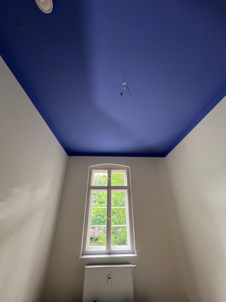 Schlafzimmer mit blauer Decke und beige gestrichenen Wänden